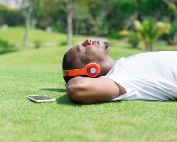 Serene Black Man Resting In Park And Listening To Music